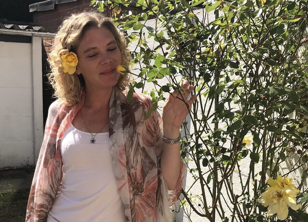 Keynote spreker zelfgenezing Nathalie ruikt aan een bloem, symboliserend de kracht van positieve gedachten in het proces van zelfgenezing.